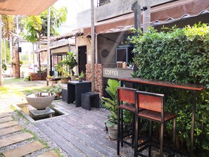 Eine Terrasse mit Kaffeestation, Sitzgelegenheiten im Freien und Pflanzen in Töpfen.