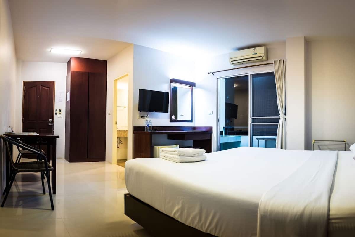 Une chambre d’hôtel comprenant un lit, un bureau, une télévision, une armoire et une salle de bain.