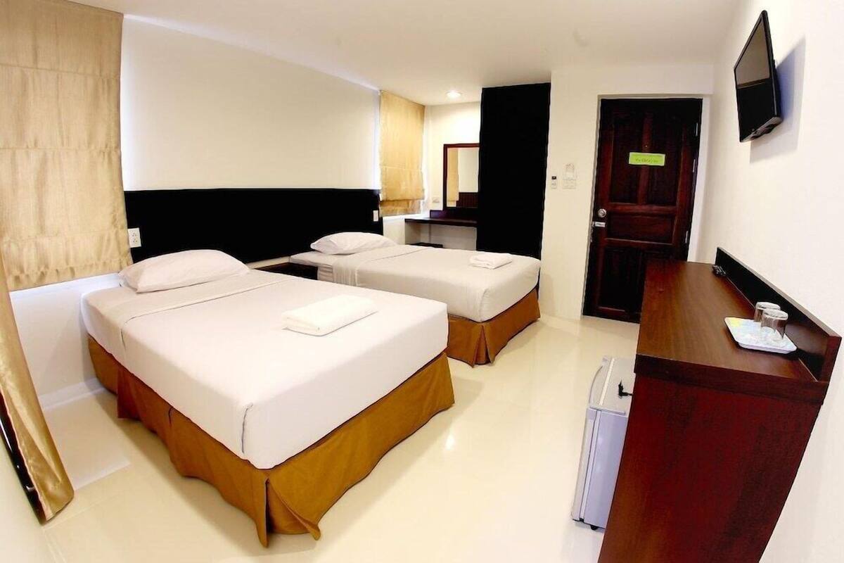 Une chambre d’hôtel avec deux lits, un bureau, une télévision et une porte.