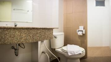 Une salle de bain équipée d’un lavabo avec un plan de travail en granit, de toilettes, d’un porte-serviettes et d’un distributeur d’essuie-tout.