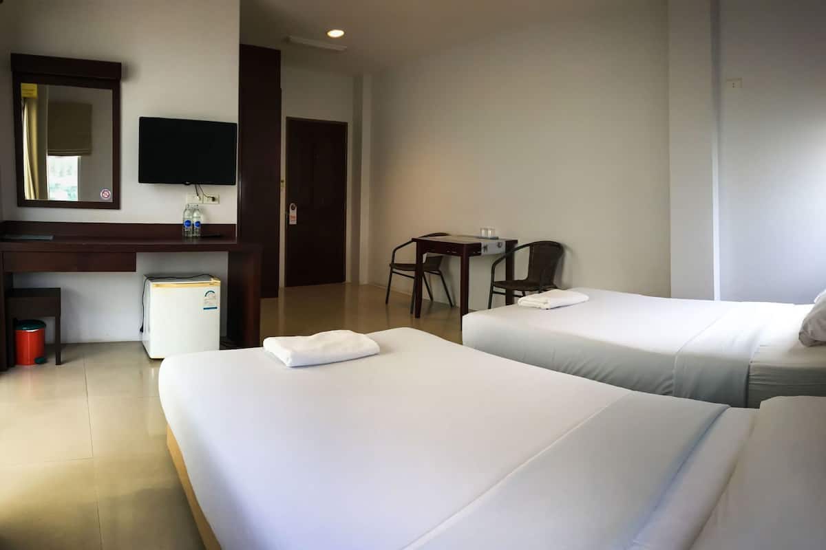 Une chambre d’hôtel avec deux lits, un bureau, une chaise, une télévision et une poubelle.