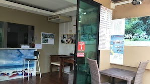 Un espace d’accueil doté d’un plancher en bois, d’un comptoir de réception, d’une cloison en verre et d’un mur orné d’une affiche.