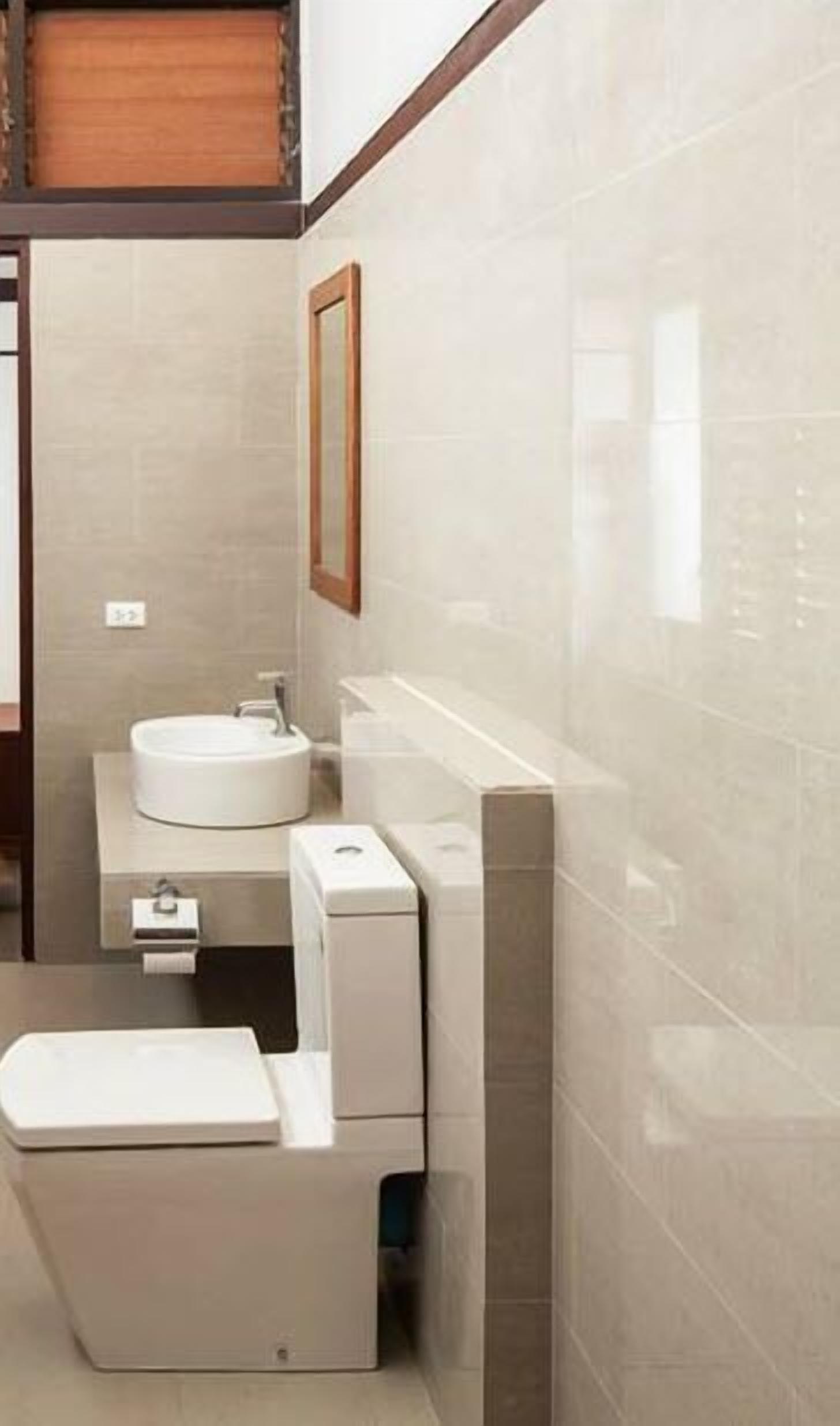 A compact, modern bathroom with a toilet, sink, and a small mirror.