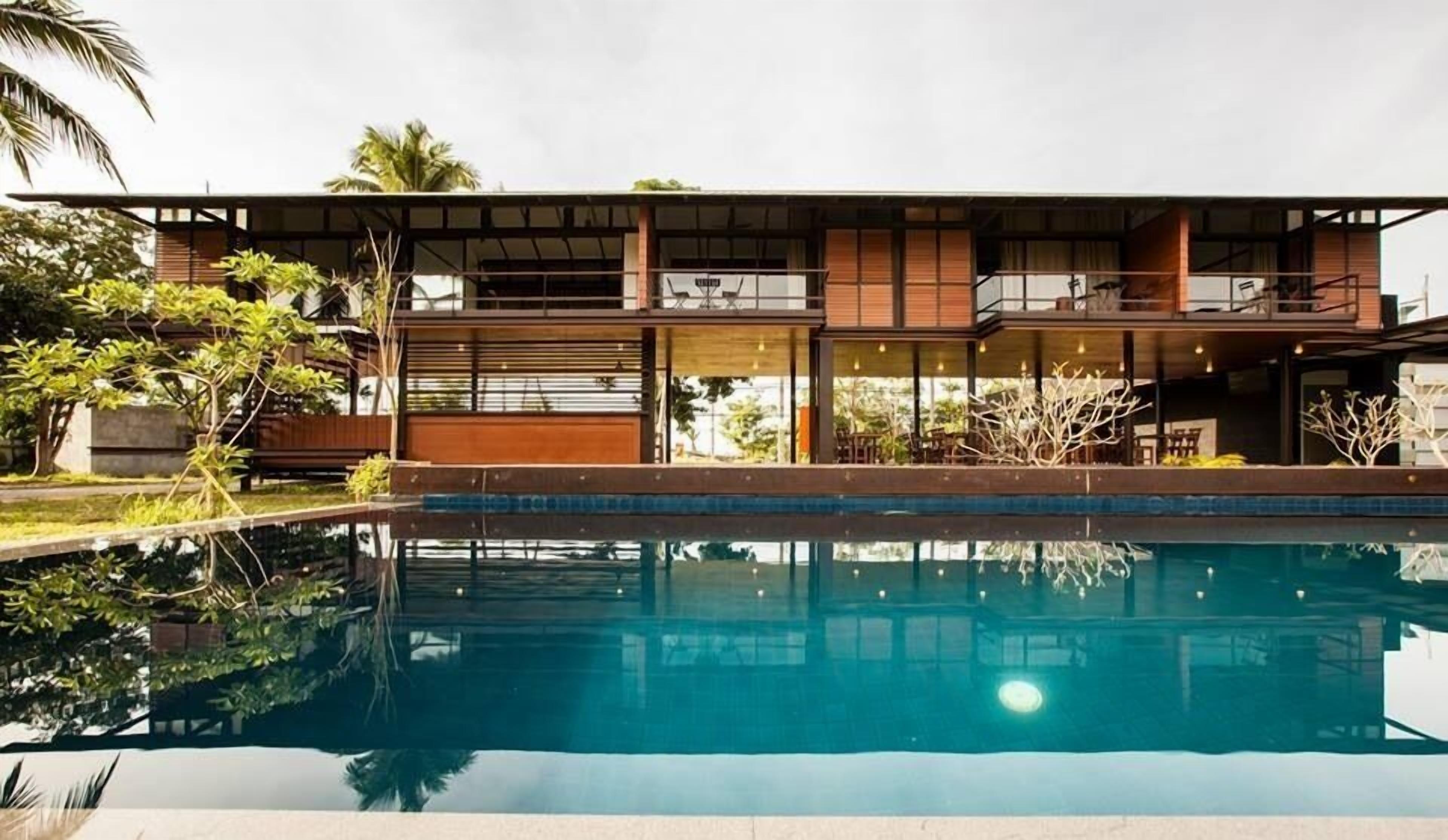 Una moderna casa a due piani con una piscina di fronte.
