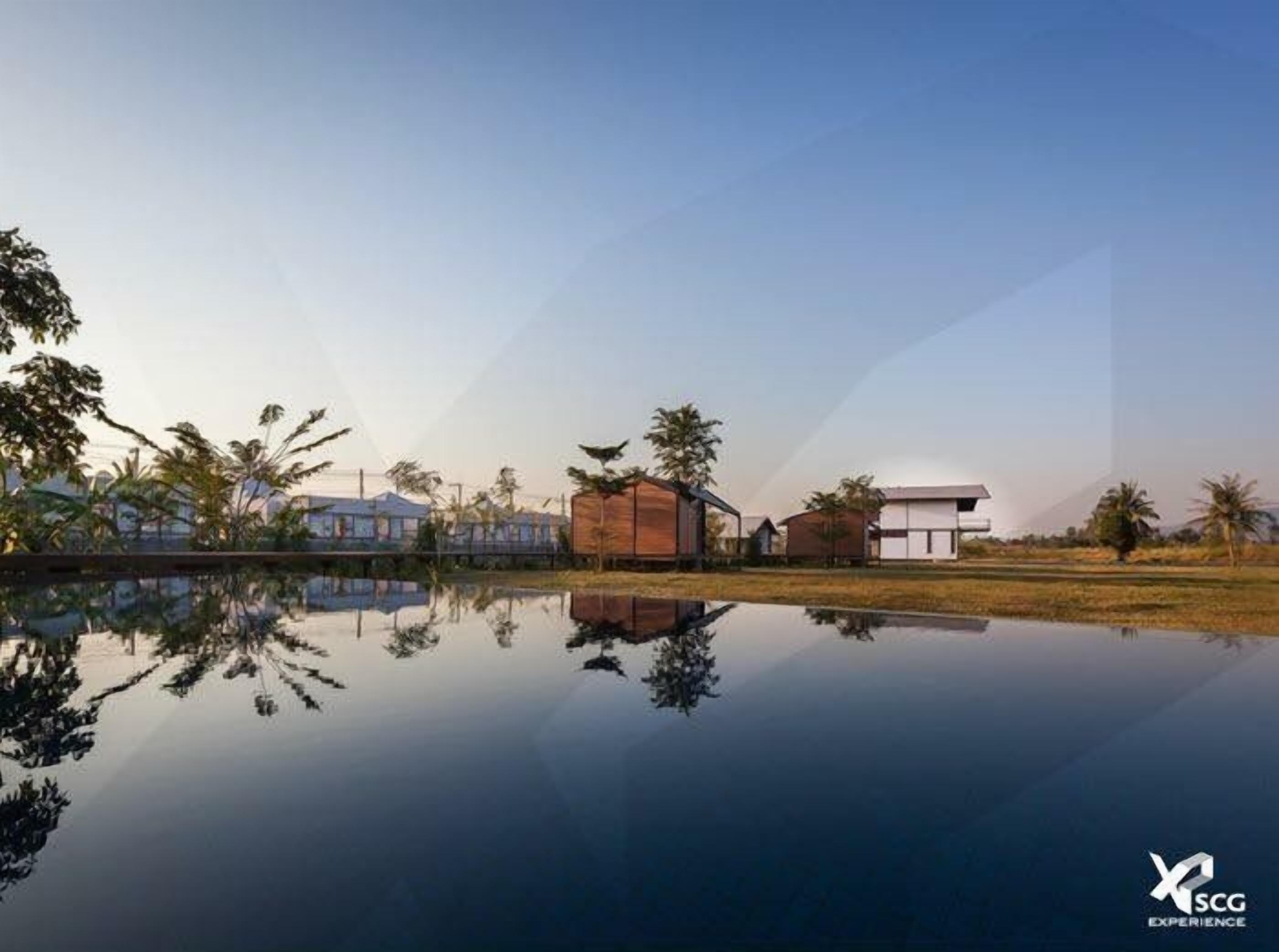 A serene lakeside setting with modern buildings, a clear sky, and a calm water surface reflecting the structures.