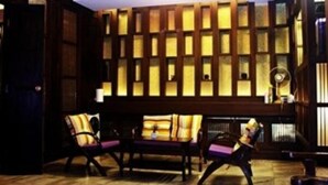A room with a wooden wall panel, a ceiling light fixture, and a seating area with two chairs. - Baan Fern Talay (Cha-am)