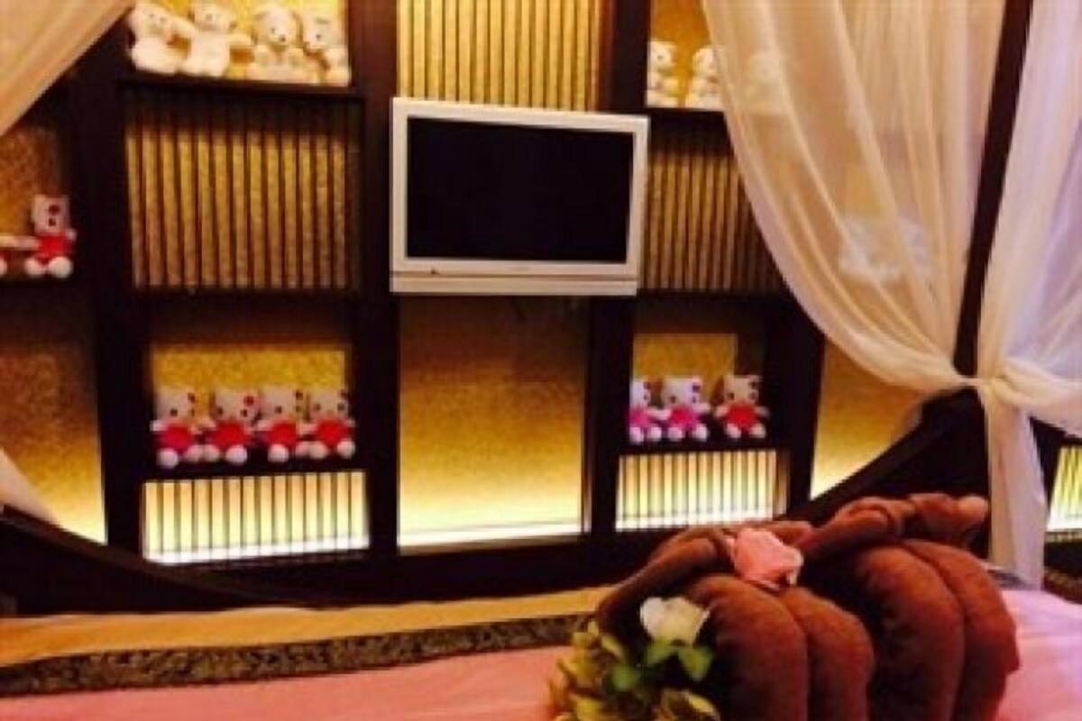 Un dormitorio con una cama, un televisor y un estante con peluches.