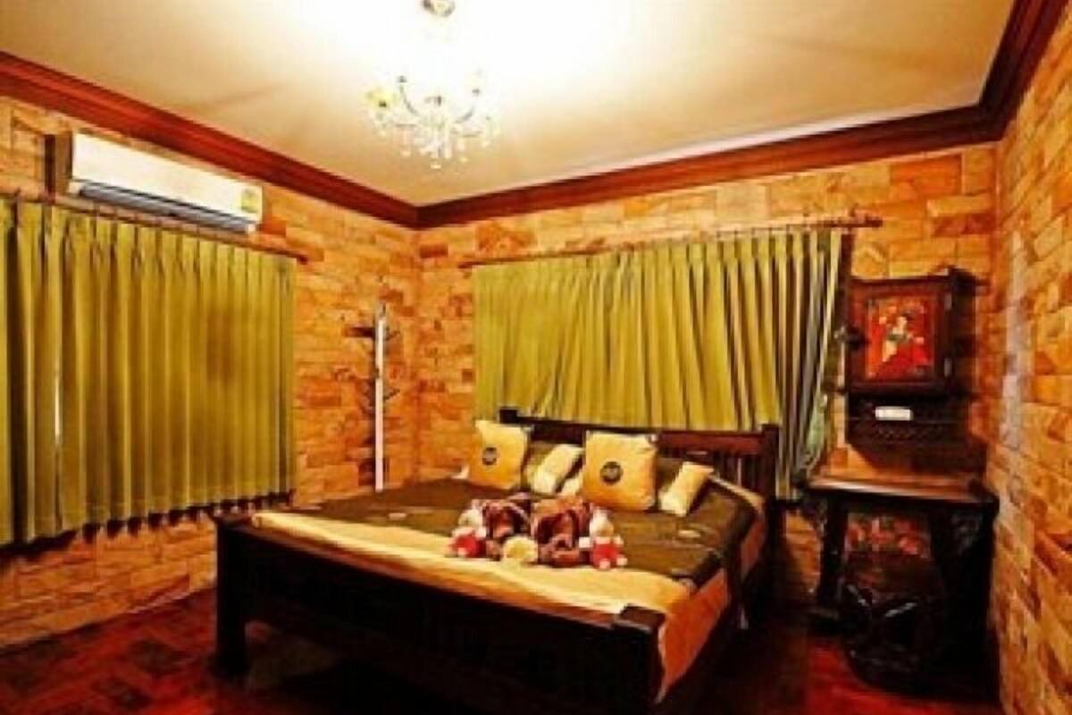 Un dormitorio con cabecera de madera, una cama con almohadas, una mesita de noche y un estante con un cuadro enmarcado.