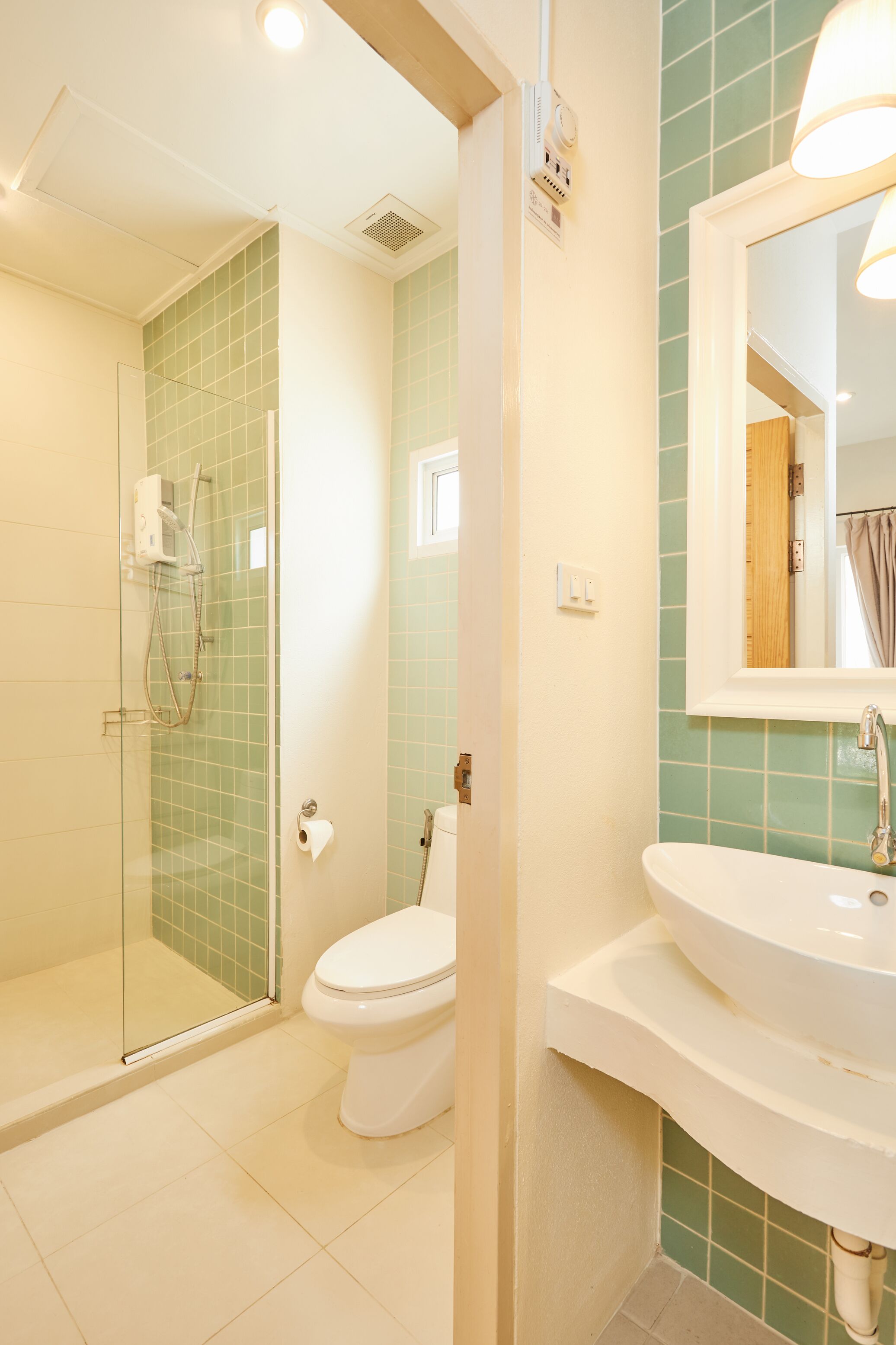 A bathroom with a glass-enclosed shower, a toilet, and a sink with a mirror above it.