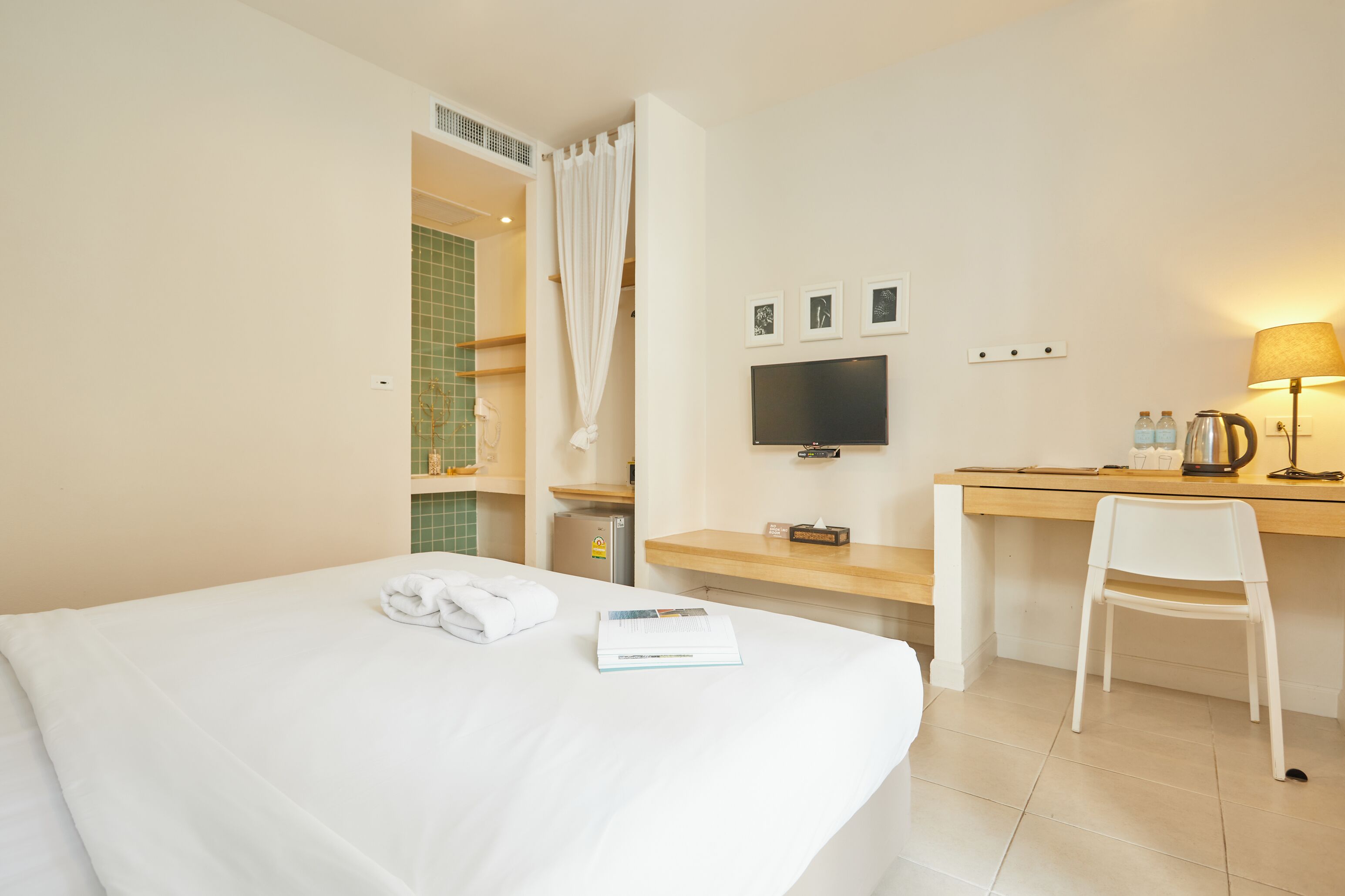 A hotel room with a bed, a desk, a chair, a television, and a bathroom visible through an open door.