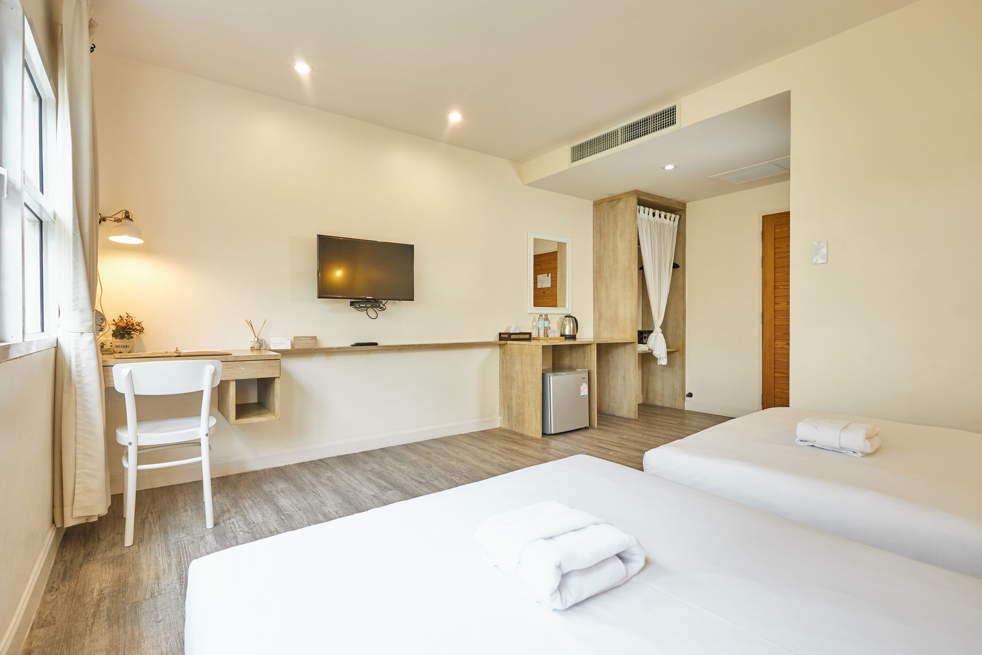 Una habitación de hotel con cama, escritorio, televisión y una pequeña cocina.
