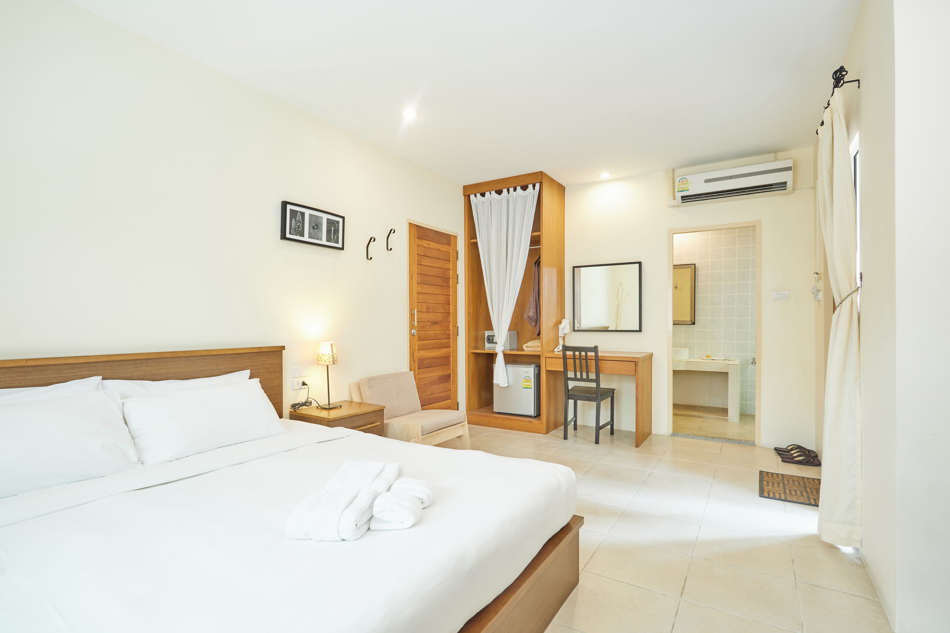 Quarto de hotel com uma cama grande, uma escrivaninha, uma cadeira e um banheiro.