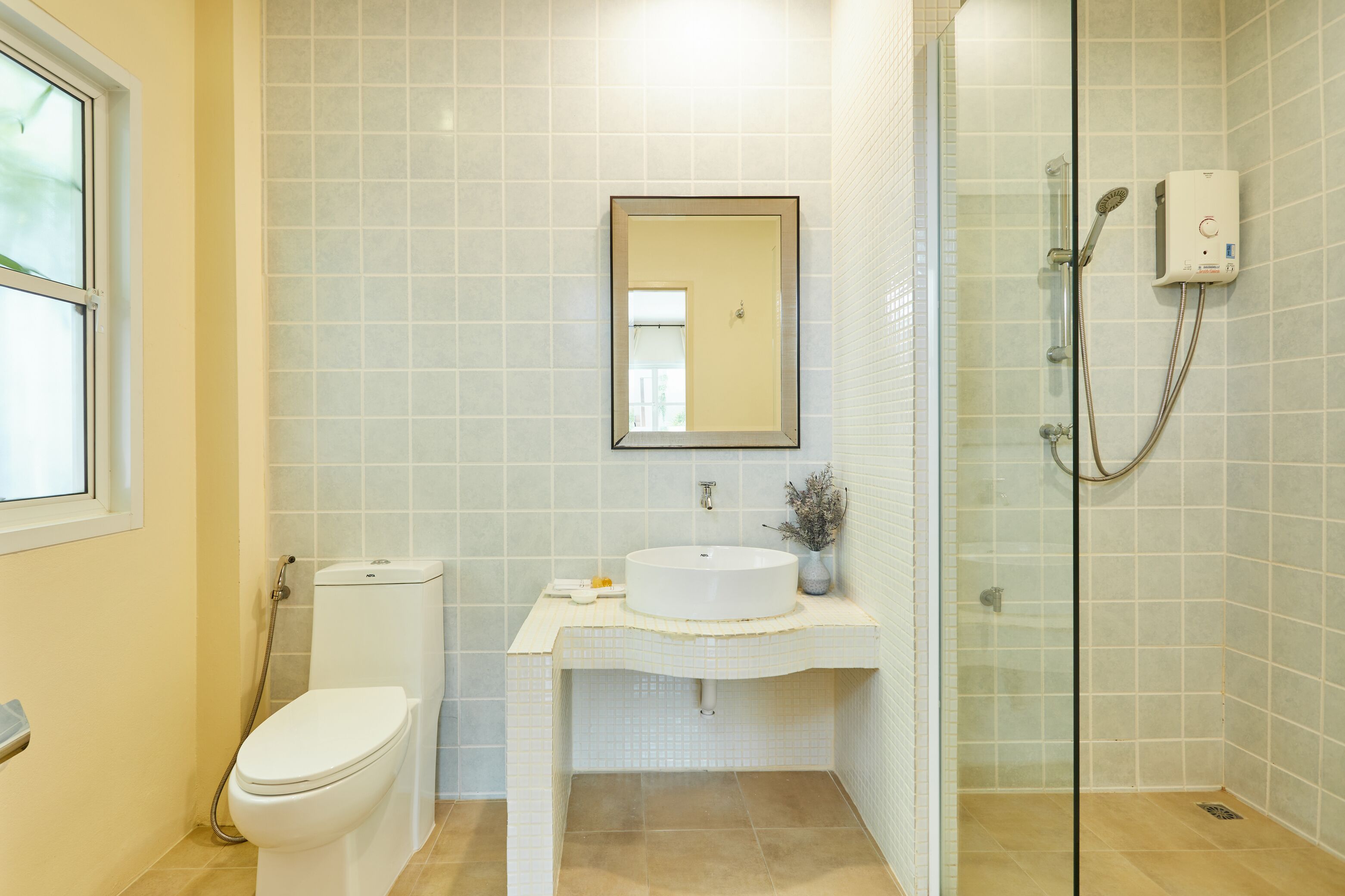 A bathroom with a toilet, sink, mirror, and shower.