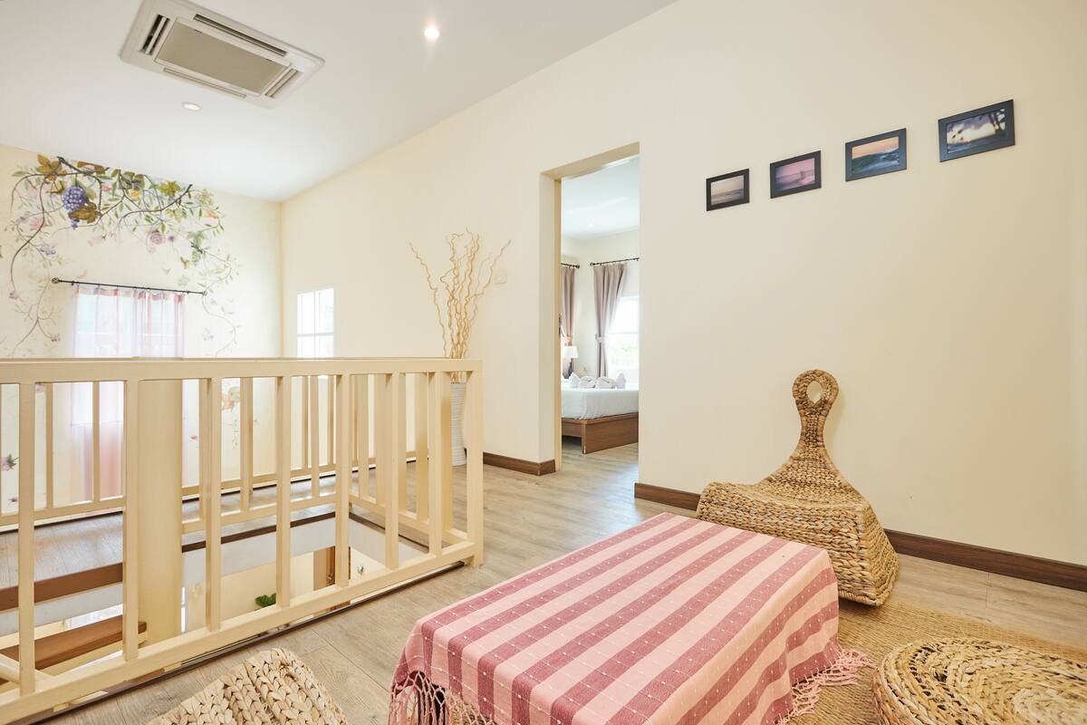 A room with a crib, a bed with a striped bedspread, a woven basket, and a wall-mounted picture frame.