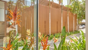 Un edificio moderno con fachada de madera, rodeado de exuberante vegetación y palmeras.