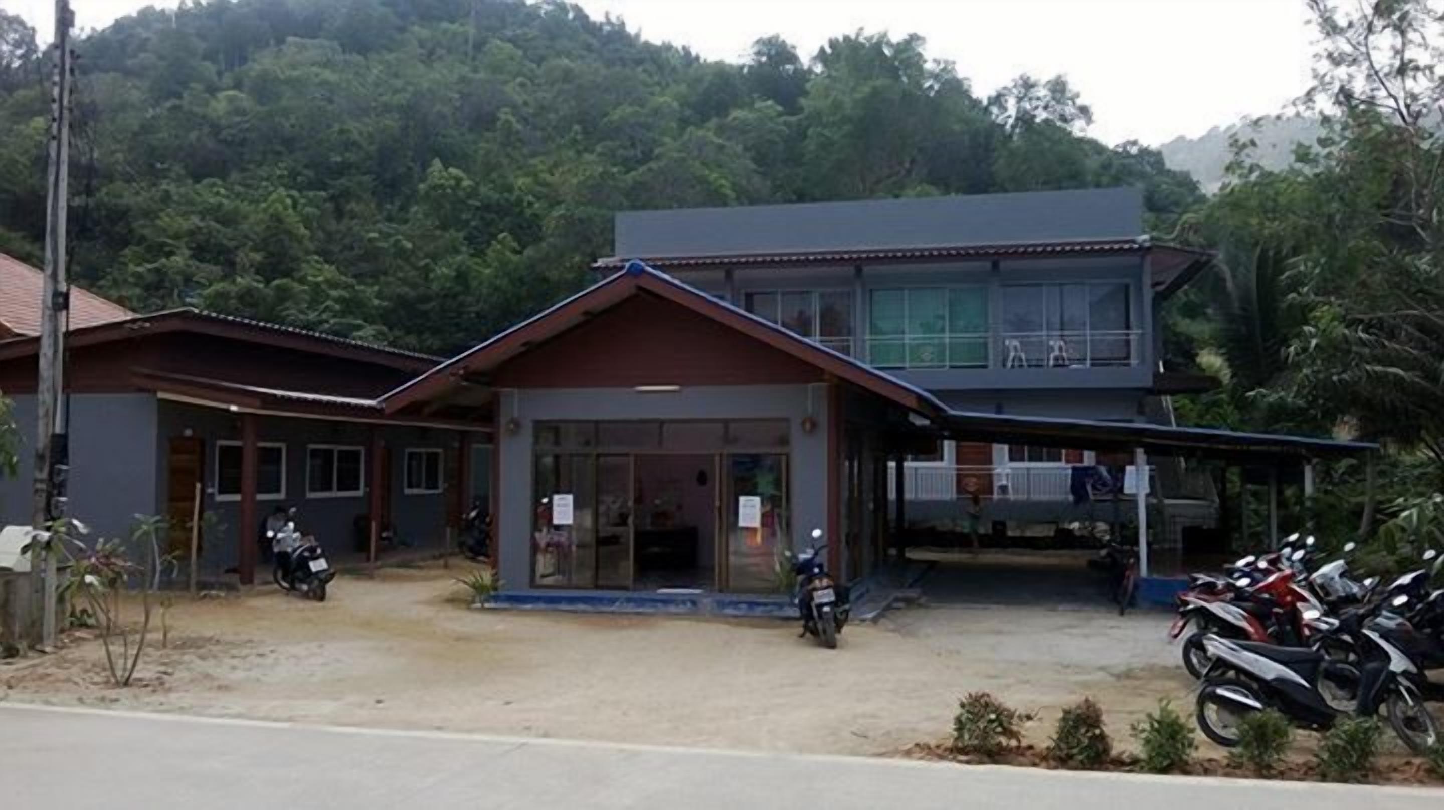 Un bâtiment à deux étages doté d’une entrée couverte et d’un espace de stationnement pour motos.