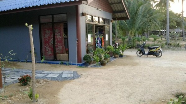 A house with a blue exterior, a red door, and a small garden with potted plants.