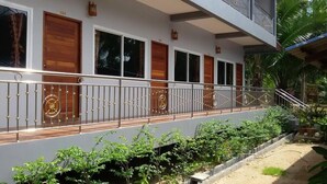 A building with a balcony, wooden doors, and a metal railing.