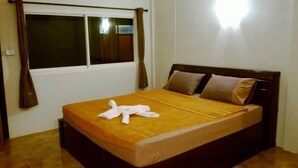 A bed with a brown headboard, a window with curtains, and a brown floor.
