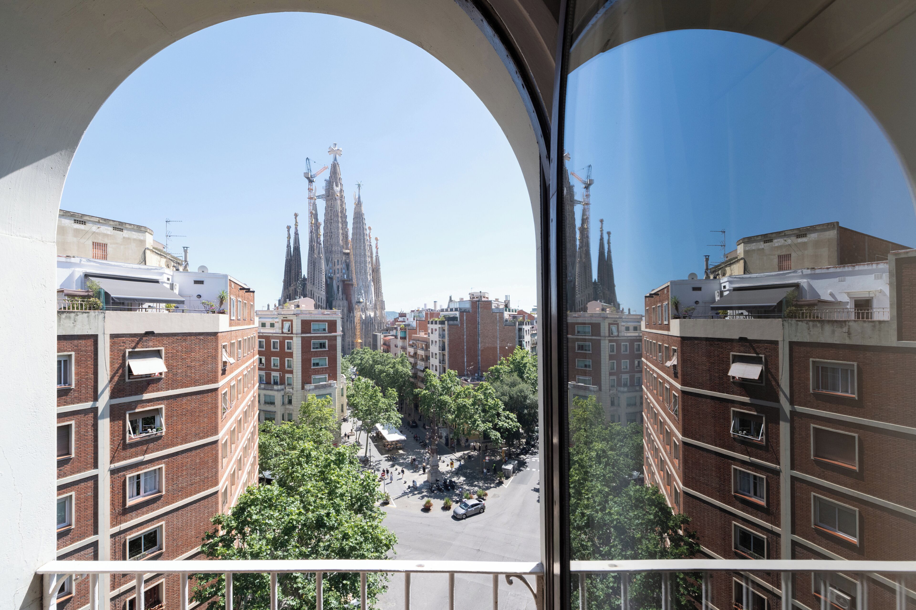 Vista a través de una ventana con cielo despejado, una calle con edificios y una catedral destacada en la lejanía.