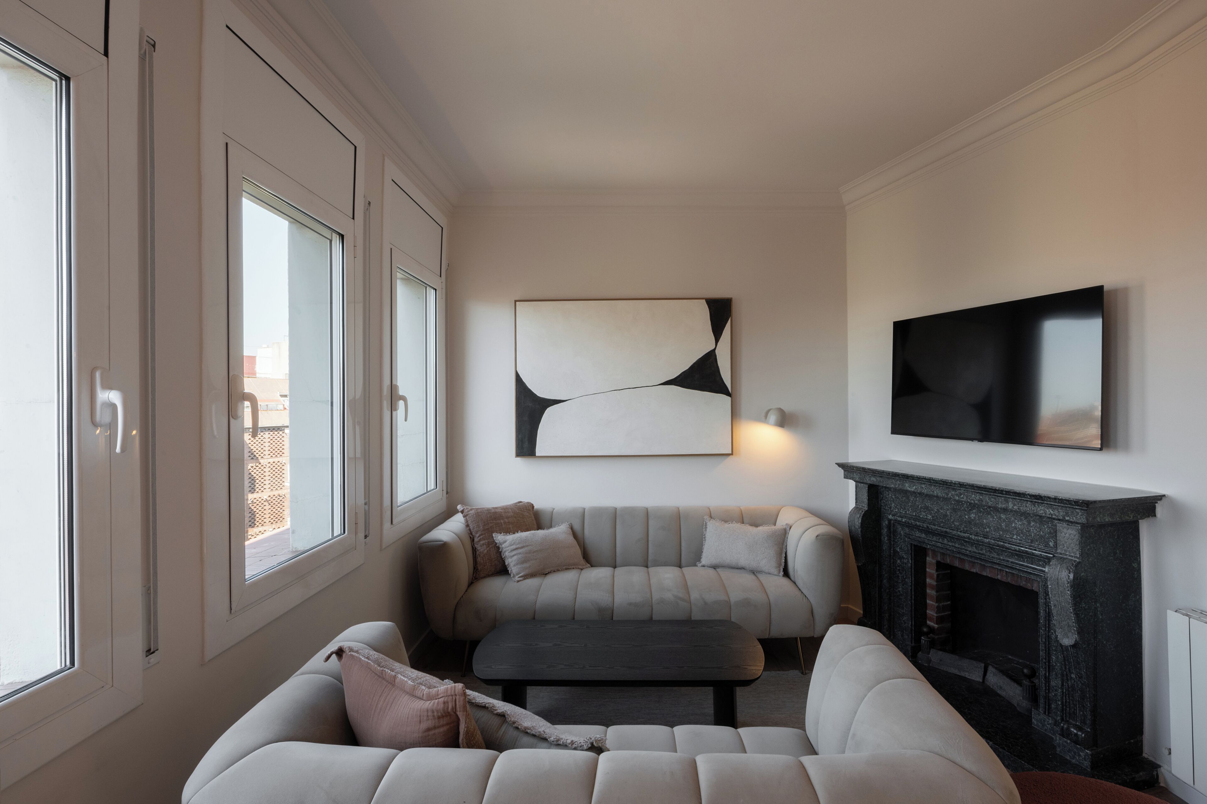 Un salon avec une cheminée, un ensemble de canapés, une table basse et un téléviseur fixé au mur.