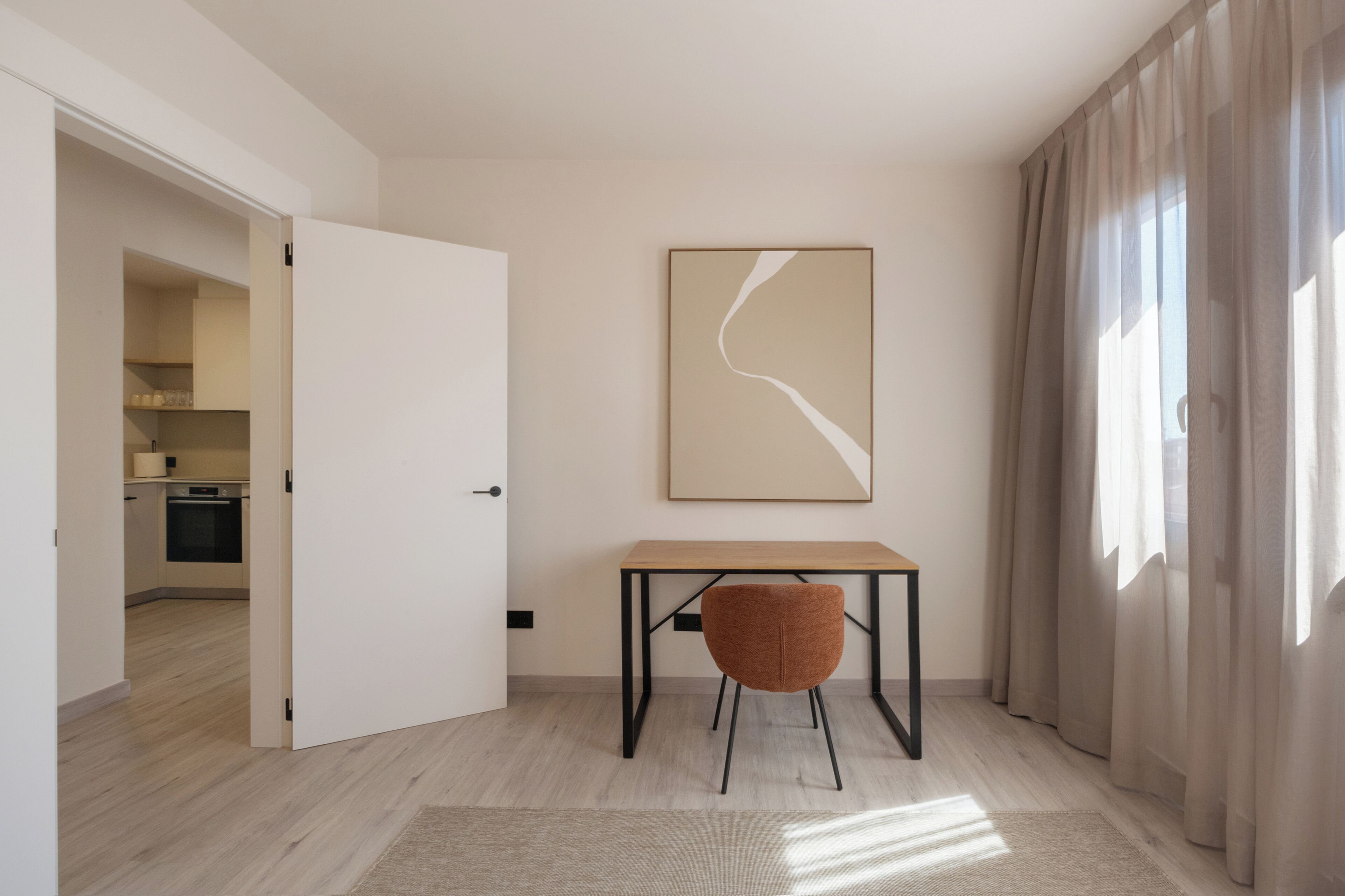 Quarto moderno e minimalista com uma mesa de madeira, uma cadeira e uma grande pintura abstrata na parede.