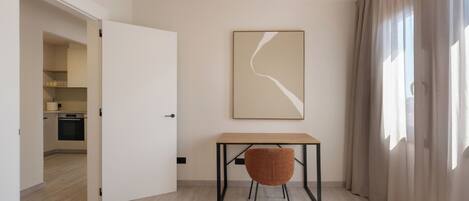 Quarto moderno e minimalista com uma mesa de madeira, uma cadeira e uma grande pintura abstrata na parede.