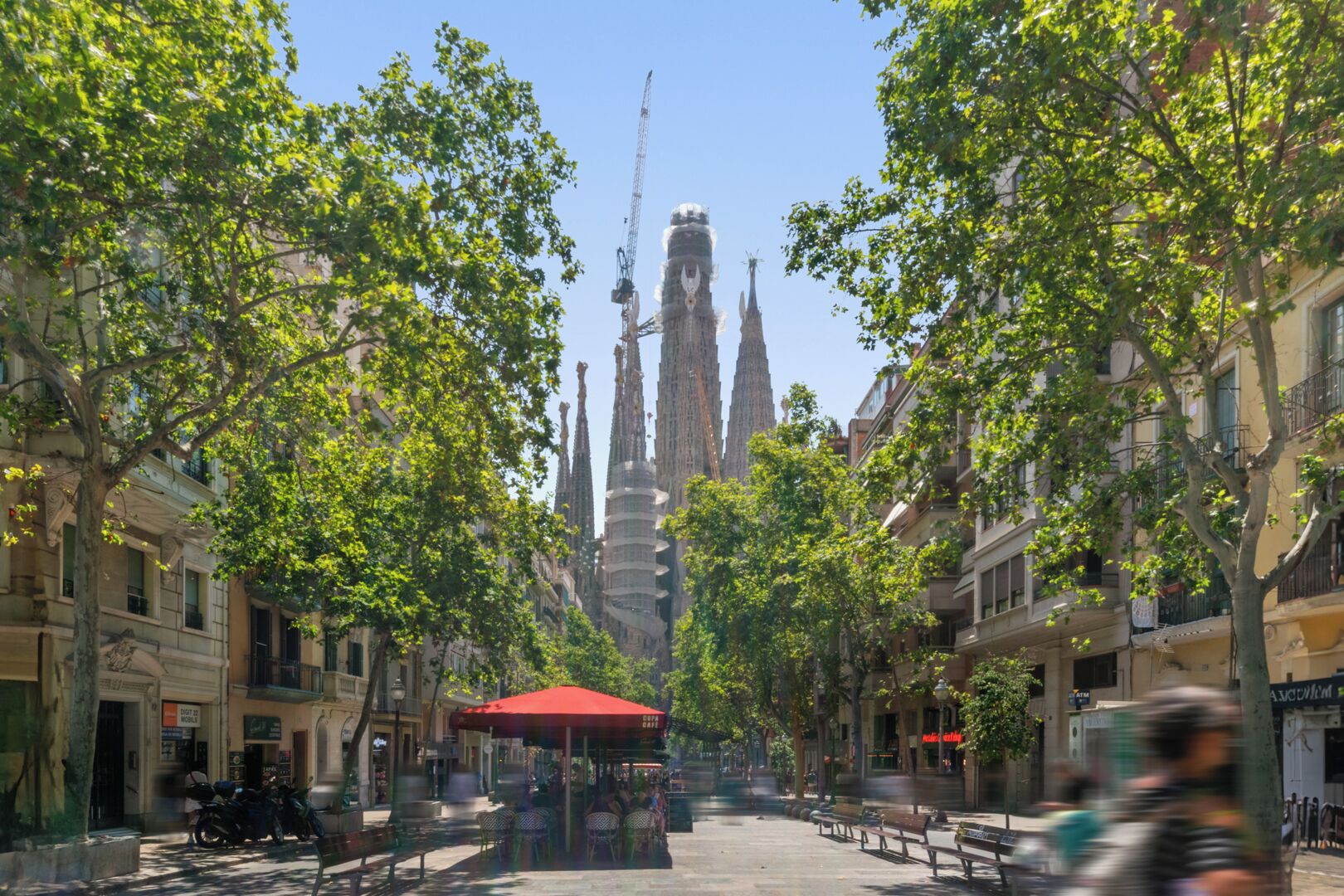 A street with trees, benches, and a red canopy.