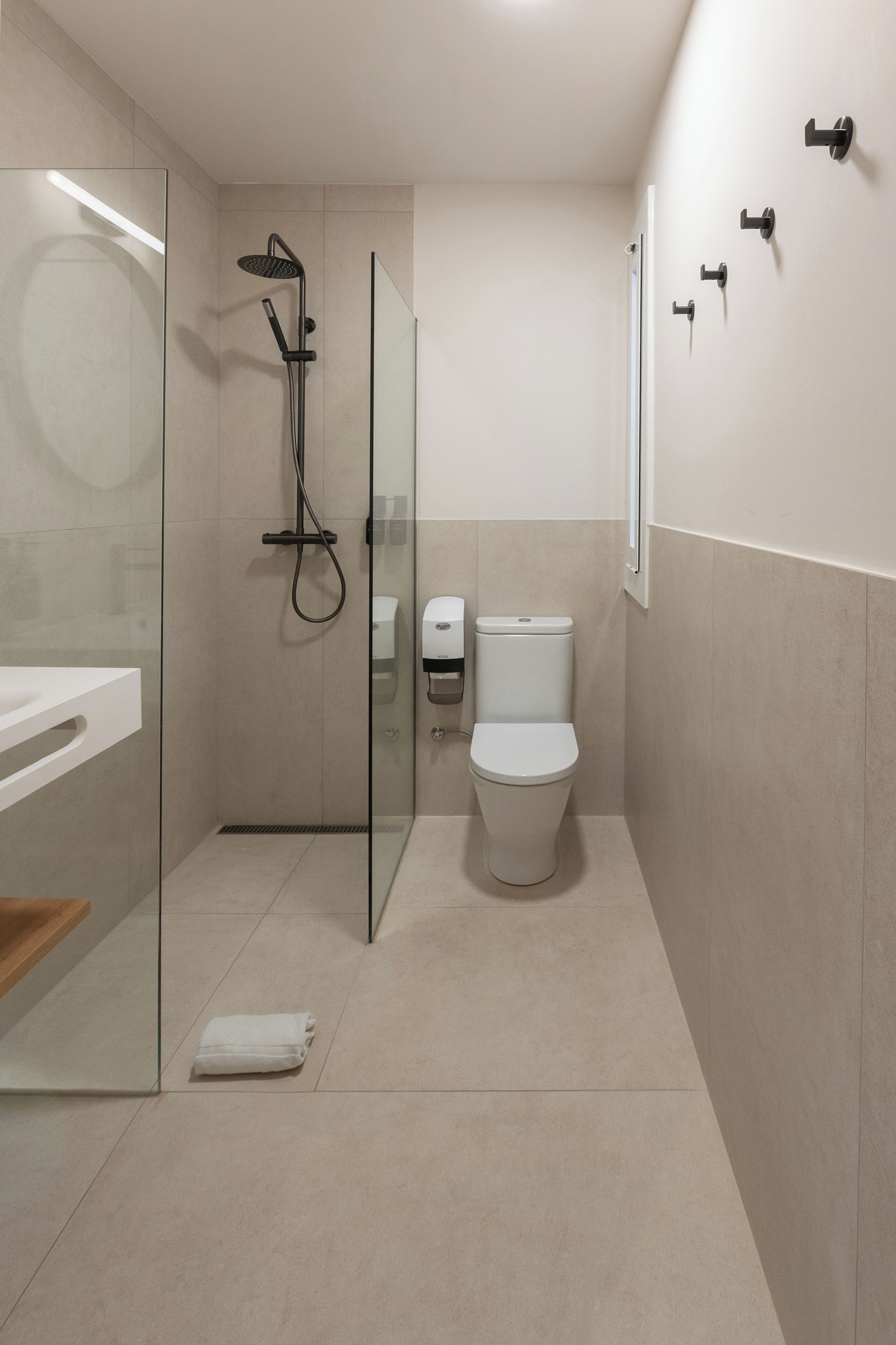 A modern bathroom with a glass-enclosed shower, a toilet, and a sink.