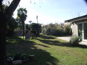 Ein Garten mit einer Terrasse, einer Rasenfläche und einem Gebäude mit einer Glastür.