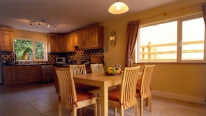 Una cocina con armarios de madera, una mesa de comedor con sillas y un frutero sobre la mesa.