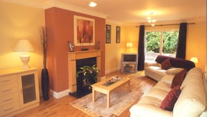 Una sala de estar con chimenea, sofá, televisor y una mesa de comedor.