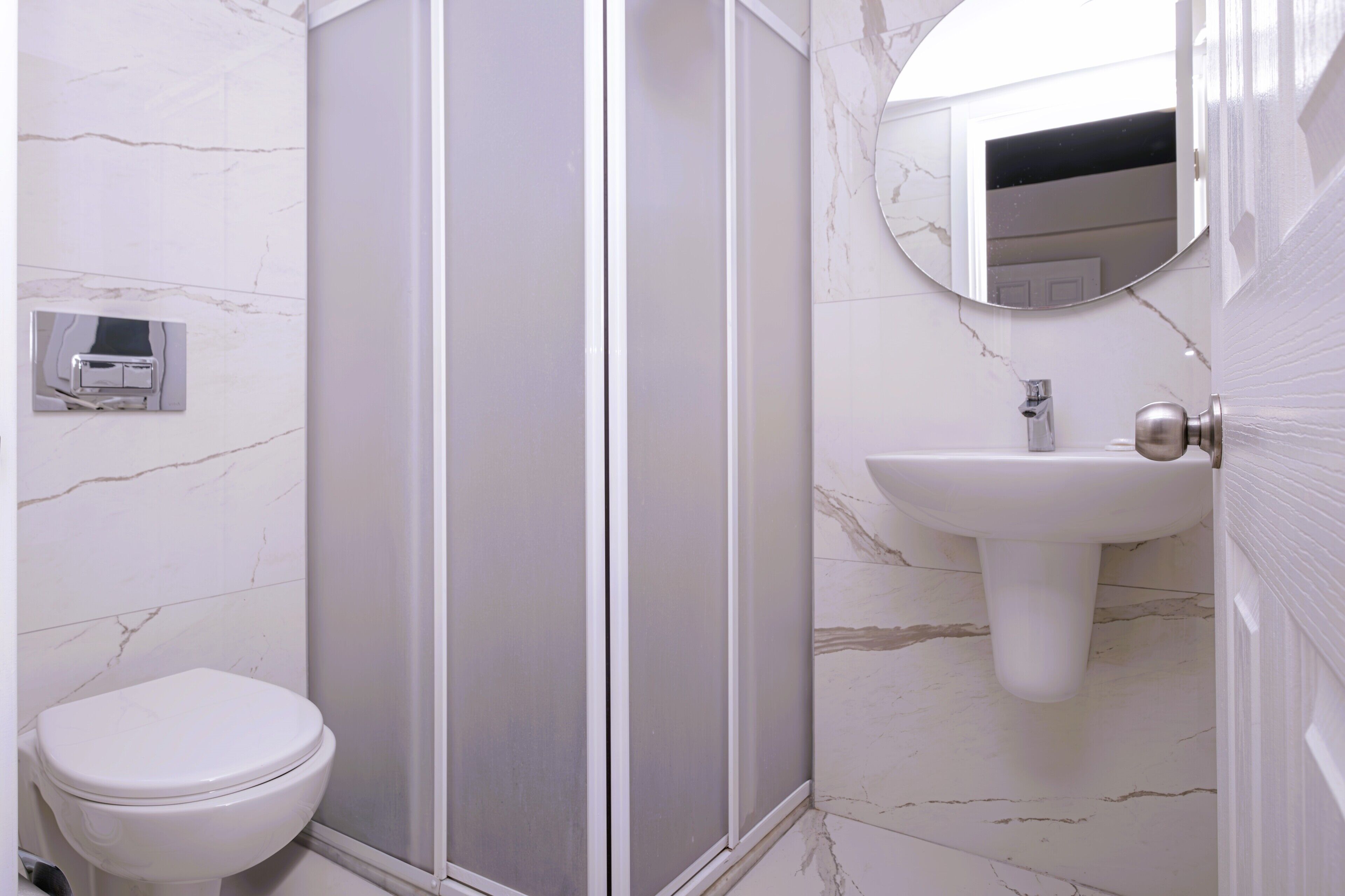 Une salle de bain comprenant des toilettes, un espace douche et un lavabo avec un miroir.