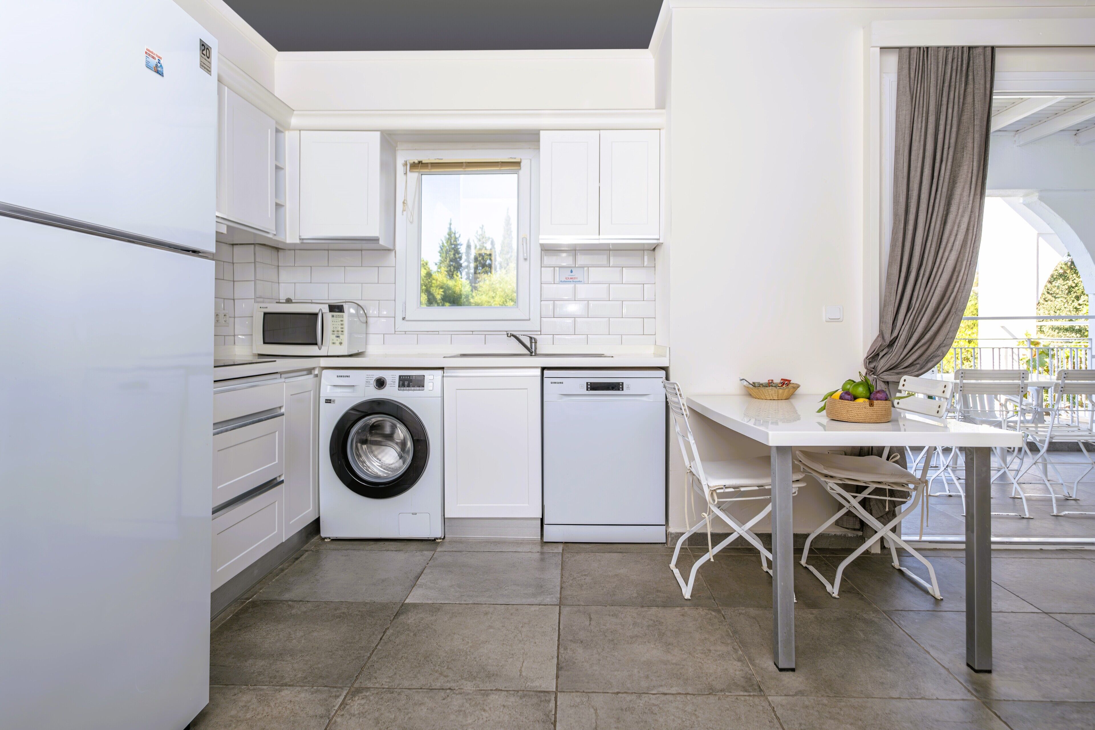 A compact kitchen with a washing machine, microwave, and dishwasher.