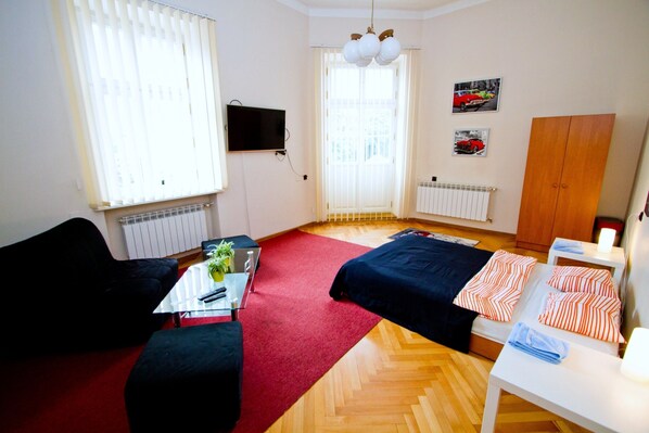 A room with a bed, a desk, a chair, a radiator, a TV, and a wardrobe.