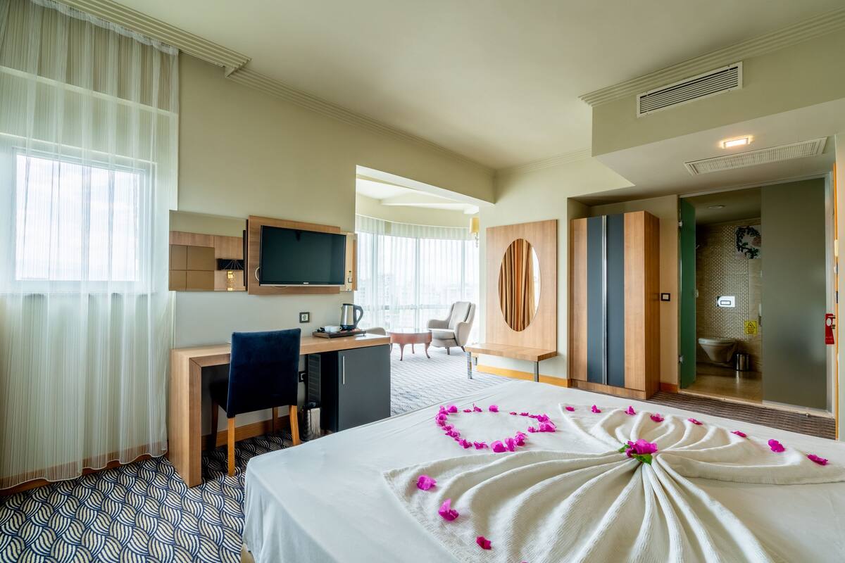A hotel room with a bed, desk, chair, and a television.