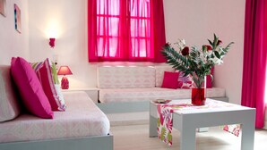 A modern living room with a sofa, a coffee table, and a vase of flowers. - Galini Apartments (Hersonissos)