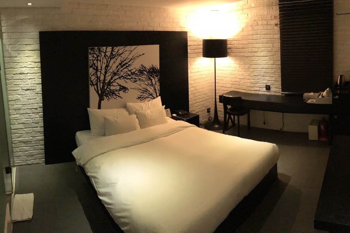 Una habitación de hotel moderna con una cama grande, un escritorio y un espejo.