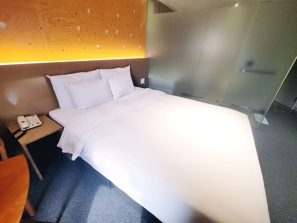 Une chambre d’hôtel avec un lit, un téléphone sur la table de chevet et une tête de lit en bois ornée de découpes circulaires.