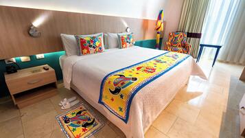 Quarto de hotel com cama, mesa de cabeceira, cadeira, mesa e janela com cortinas.