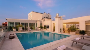 A rooftop pool with lounge chairs and a glass-enclosed building. - Four Points By Sheraton Barranquilla (Barranquilla)