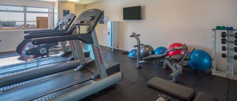 A gym with treadmills, weight machines, and exercise balls.