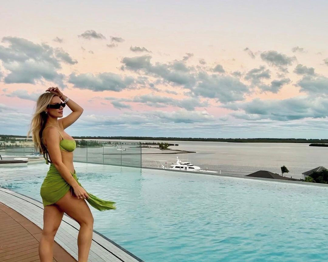 Eine Frau in einem grünen Badeanzug am Pool, im Hintergrund ein Boot.