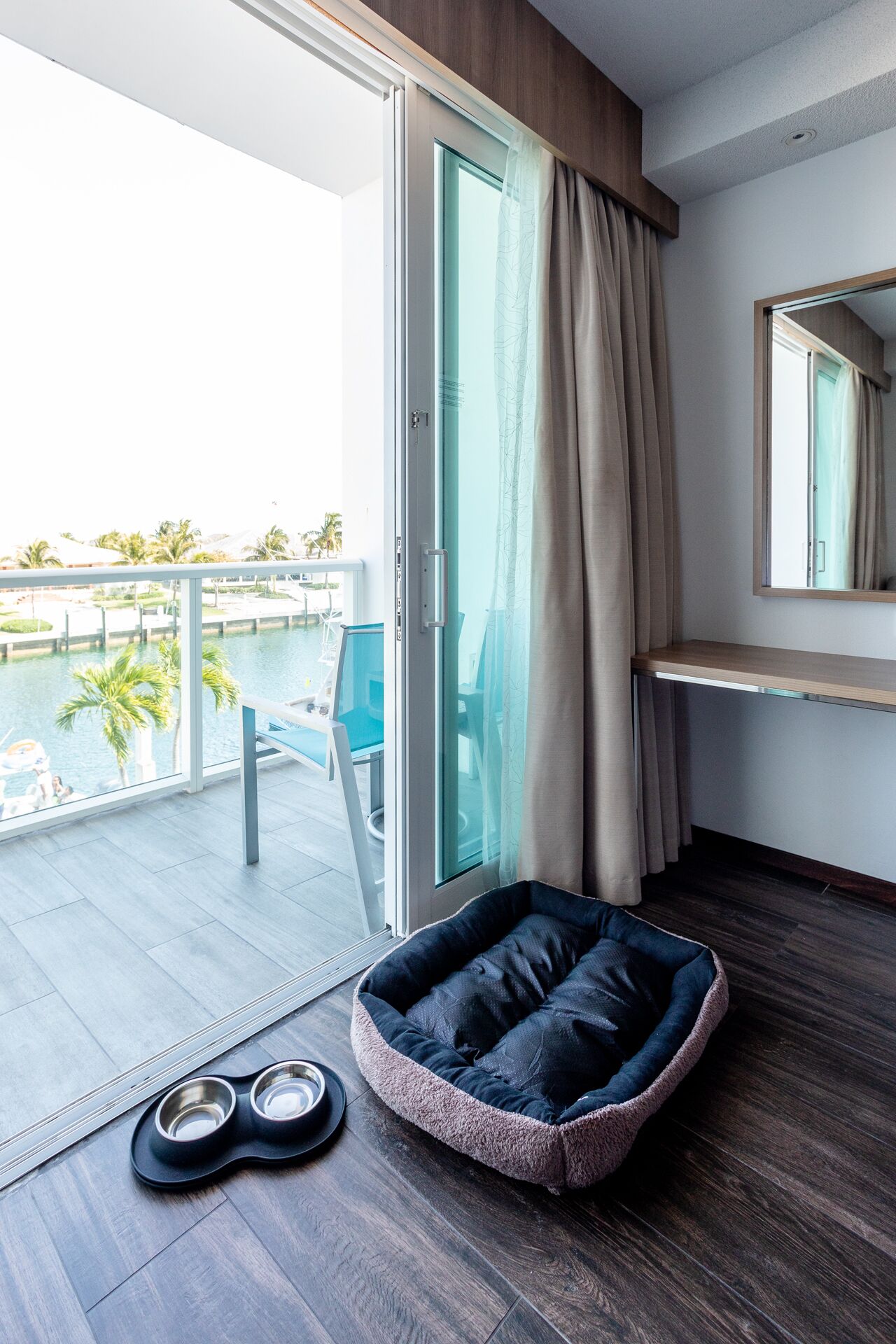 Een moderne hotelkamer met een schuifdeur naar een balkon met uitzicht op het zwembad.
