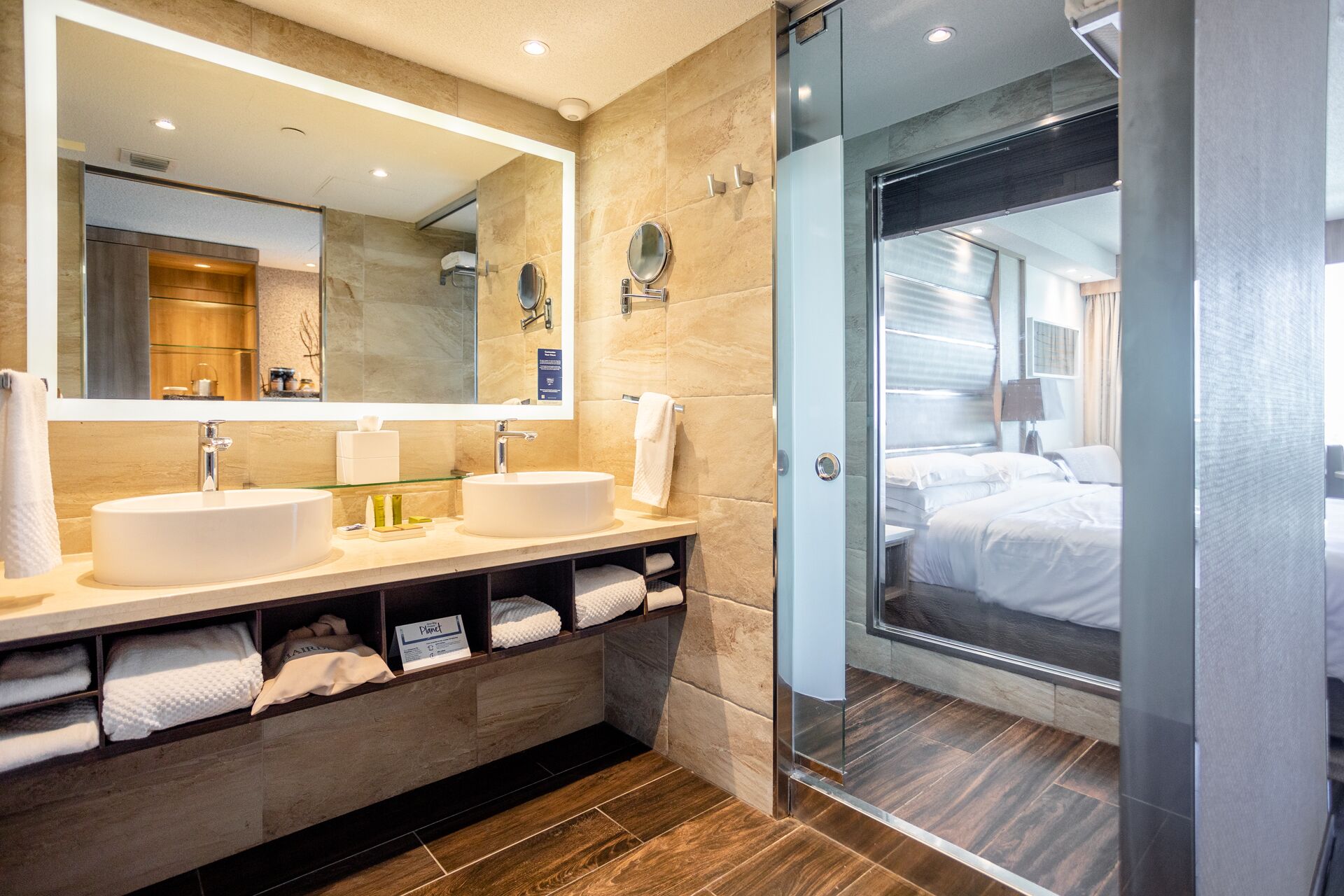 A modern bathroom with two sinks, a large mirror, and a glass shower enclosure.