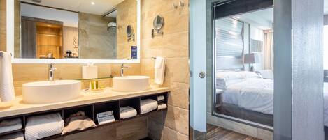 A modern bathroom with two sinks, a large mirror, and a glass shower enclosure.