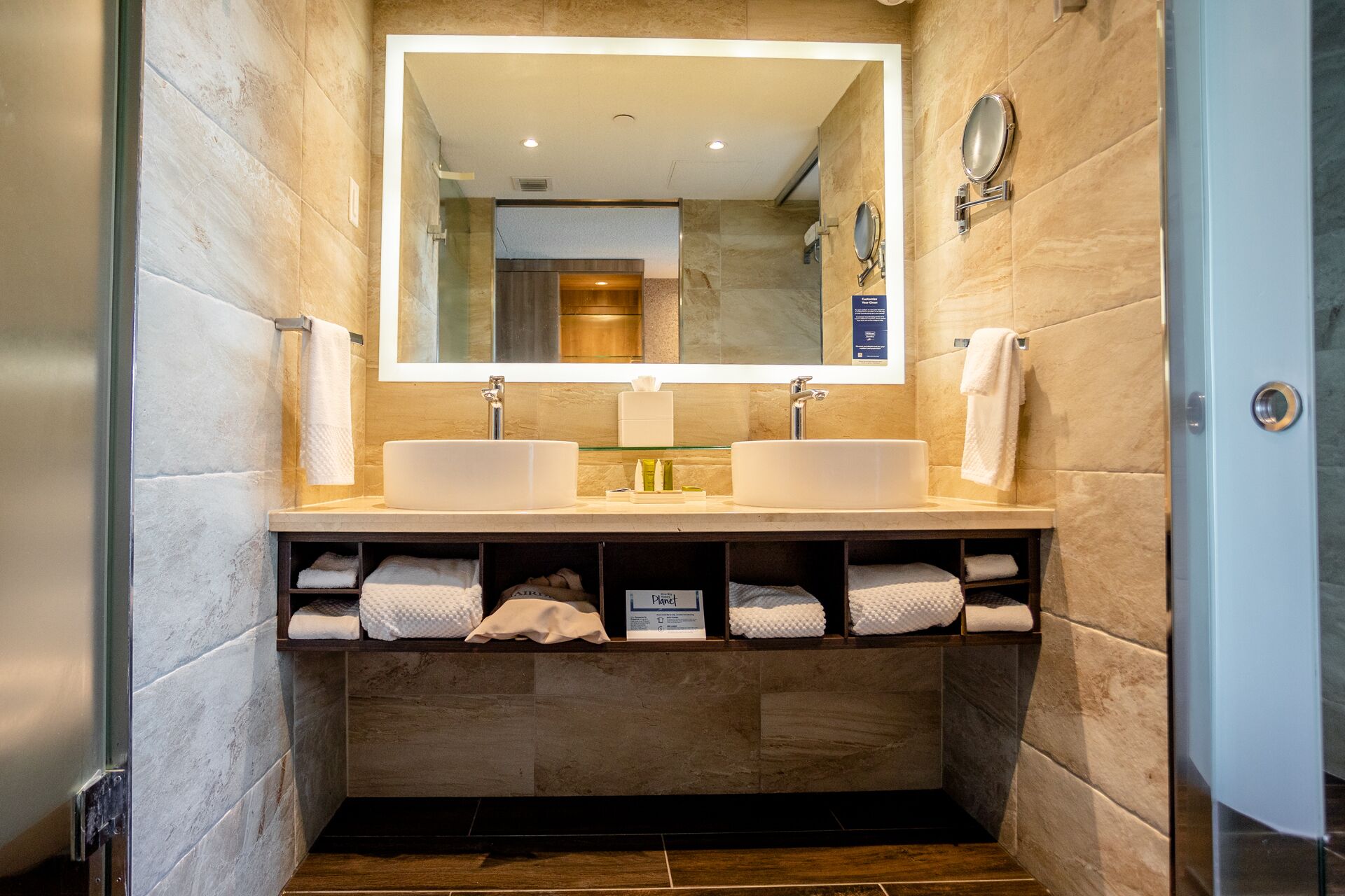 A modern bathroom with two sinks, a large mirror, and a towel rack.