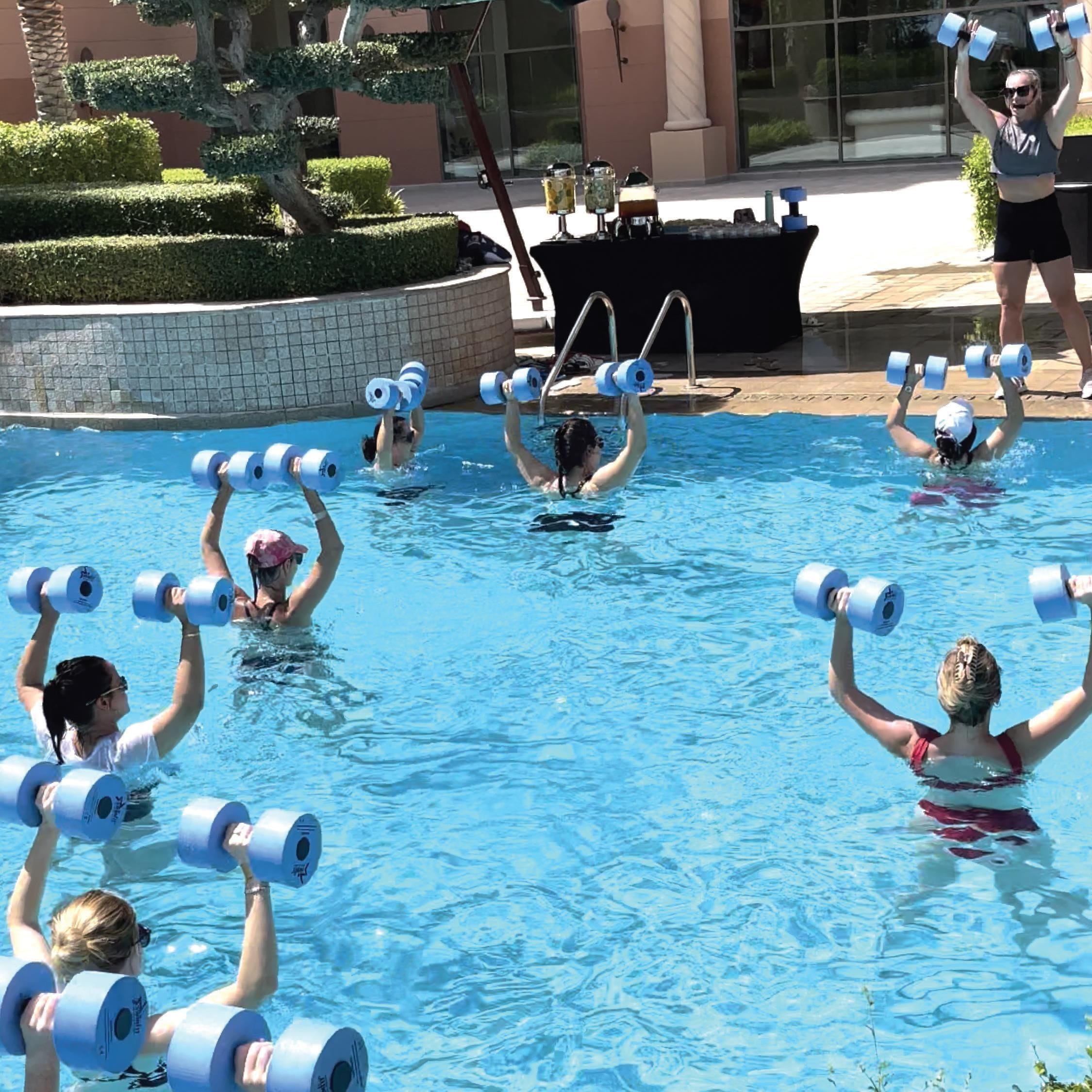 A swimming pool with people holding dumbbells.