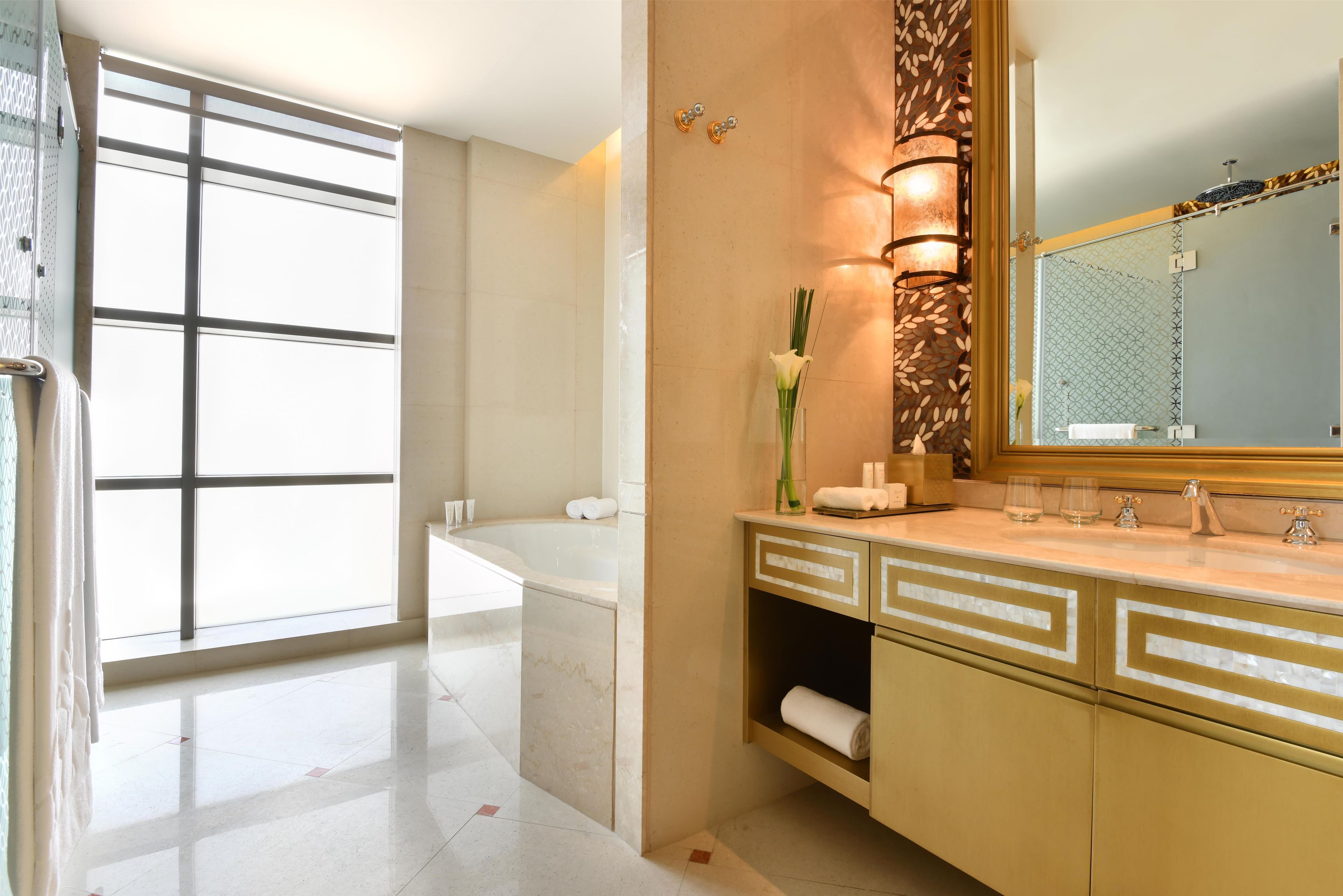 A modern bathroom with a bathtub, a vanity with a mirror, and a large window.