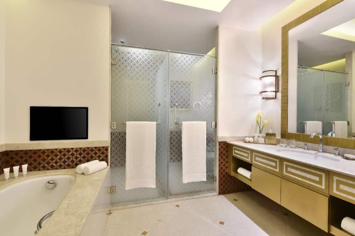 Une salle de bain moderne dotée d’une douche à parois de verre, d’une grande baignoire et d’un meuble-lavabo avec un miroir.